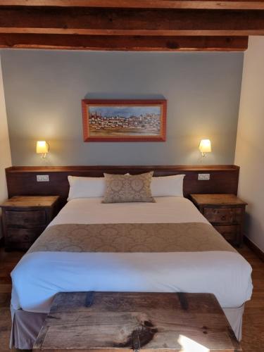 a bedroom with a large bed with two night stands at Posada Torre Palacio La Taxuela in Villanueva la Lastra