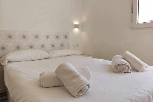 una camera da letto con un letto bianco e asciugamani di Bonito apartamento en 2º línea de playa & parking a Málaga