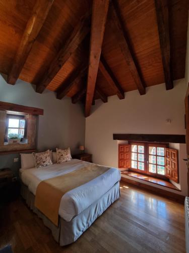 a bedroom with a large bed and two windows at Posada Torre Palacio La Taxuela in Villanueva la Lastra