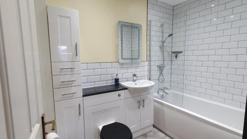 a bathroom with a sink and a toilet and a tub at Skiddaw. 20 Greta Grove House in Keswick