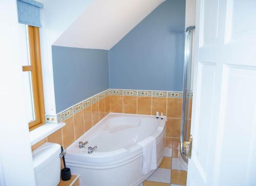 Habitación con baño con bañera blanca. en Dingle Courtyard Cottages 4 Bed en Dingle