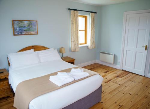 1 dormitorio con 1 cama blanca grande y toallas. en Dingle Courtyard Cottages 4 Bed en Dingle