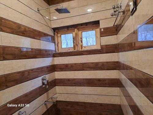 a bathroom with wooden walls and a window at Al-Ayaan Guest House in Pahalgām