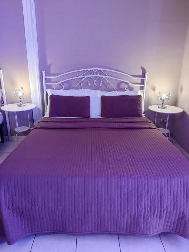 a purple bed in a bedroom with two tables at Hotel Biscari in Catania
