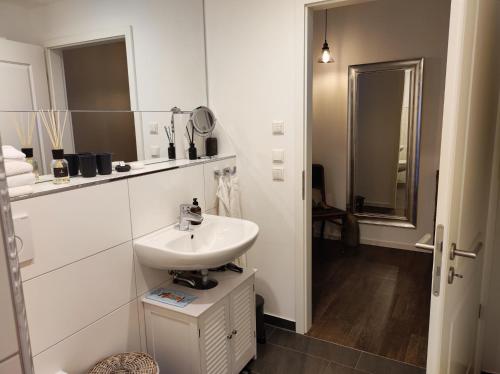 Baño blanco con lavabo y espejo en 5-Sterne-City Apartment Rendsburg, en Rendsburg