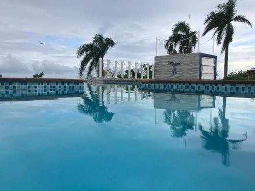 a large swimming pool with blue water and palm trees at Oasis en la naturaleza Rancho alto bonito in Las Galeras