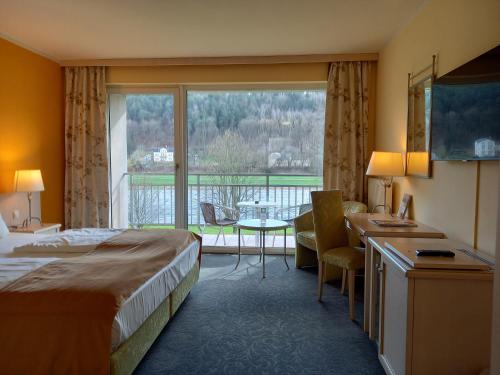 a hotel room with a bed and a desk and a window at Parkhotel Bad Schandau mit SPA in Bad Schandau
