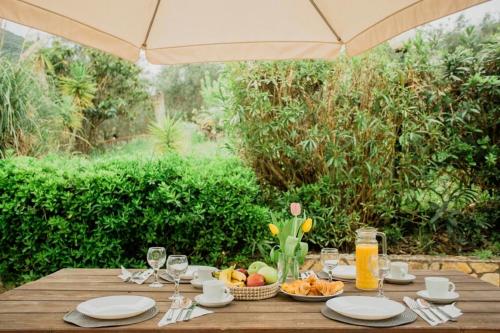 drewniany stół z talerzami i szklankami soku pomarańczowego w obiekcie Ionian Escape Seaview Apartments w mieście Mesongi