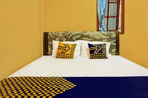 a bed with four pillows on it in a room at SPOT ON 92450 Homestay Simpang Panji Suroso Syariah in Malang