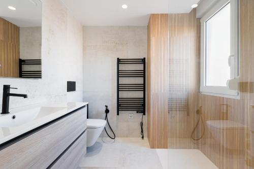 a bathroom with a sink and a toilet and a window at Sunrise Center Suites in Torrevieja