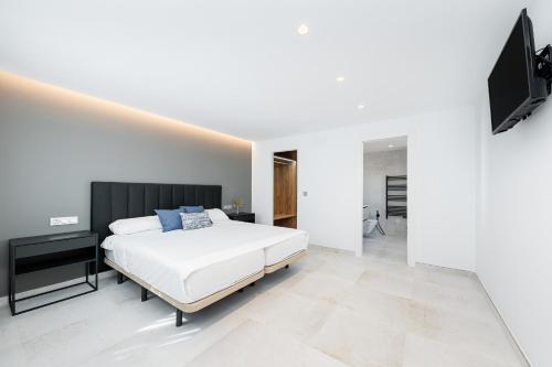 a white bedroom with a bed and a flat screen tv at Sunrise Center Suites in Torrevieja