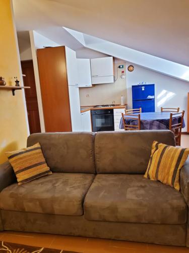 サン・ヴァンサンにあるMansarda Via Chanouxのキッチン付きのリビングルームに茶色のソファがあります。