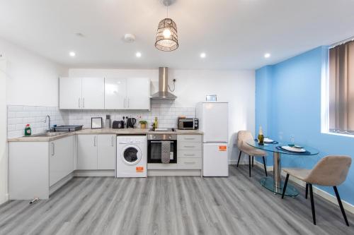 una cocina con electrodomésticos blancos, mesa y sillas en Charming 1BR in Stockport Center en Stockport