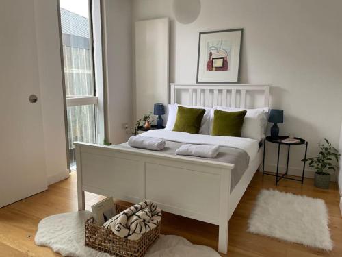 a white bed with green pillows in a bedroom at Shoreditch Cosy Flat, next to Van Gogh exhibition in London