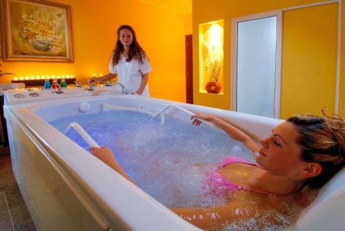 a woman in a bath tub with a woman standing in it at Apollo Spa Resort - Ultra All Inclusive - Indoor Pool, Steam Bath & Sauna - Aphrodite Beauty Spa in Golden Sands