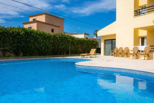 a swimming pool with chairs next to a house at Apto con Terraza 102 in Cala Millor