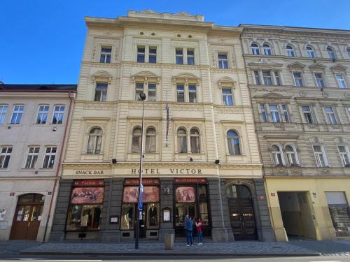 un gran edificio con gente parada frente a él en Hotel Victor, en Praga