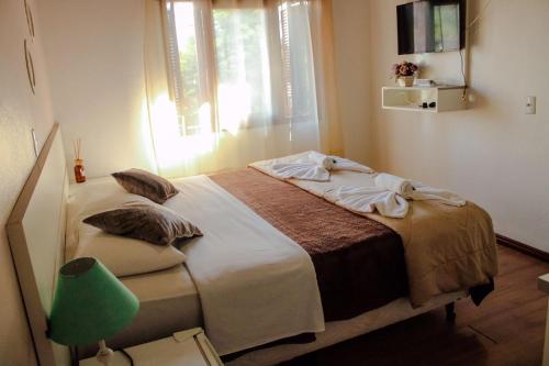 una camera da letto con un letto con una finestra e una lampada verde di Pousada Cantinho a Gramado