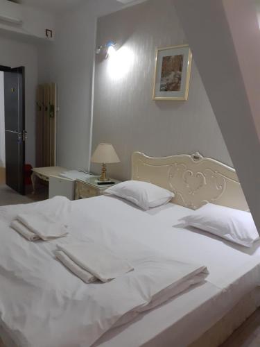 1 cama blanca grande con sábanas y almohadas blancas en Nevis Fundeni en Bucarest