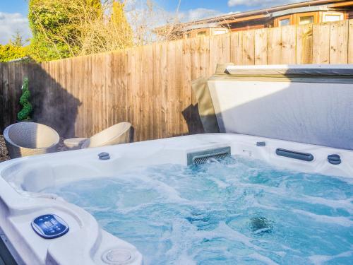 a hot tub in a backyard with a wooden fence at California Cottage - Uk42876 in Wilberfoss