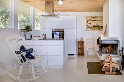 uma cozinha branca com uma cadeira e uma lareira em Villa Dyyni - South Facing - Seafront - Jacuzzi em Helsinque