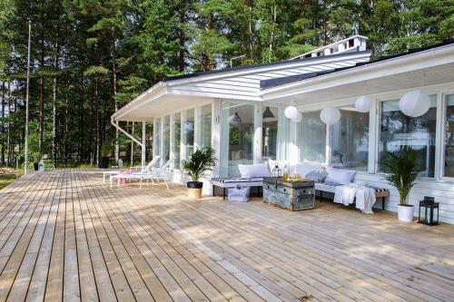 um pavilhão com mobiliário branco num deque de madeira em Villa Dyyni - South Facing - Seafront - Jacuzzi em Helsínquia