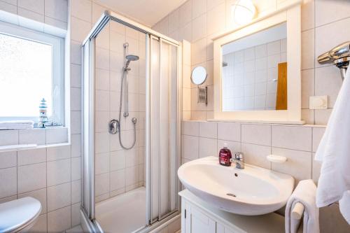 y baño blanco con lavabo y ducha. en Haus Seemeile Wohnung 2 20, en Büsum