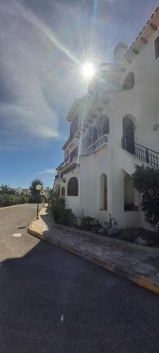 duży biały budynek ze słońcem świecącym za nim w obiekcie Casa Clare, Cabo Roig w mieście Cabo Roig