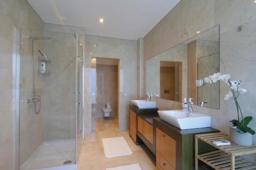 un ampio bagno con due lavandini e una doccia di Luxury Townhouse, in Tavira Centre with shared pool a Tavira