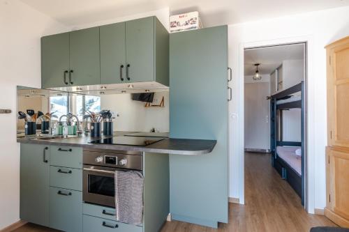 une cuisine avec des placards verts et un comptoir dans l'établissement L'Orée des Aravis - Au pied des pistes, à Manigod