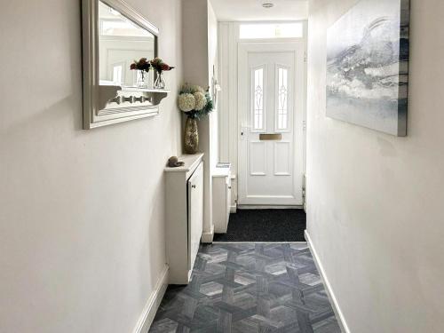 um corredor com uma porta branca e piso em azulejo em Highcross em Poulton le Fylde