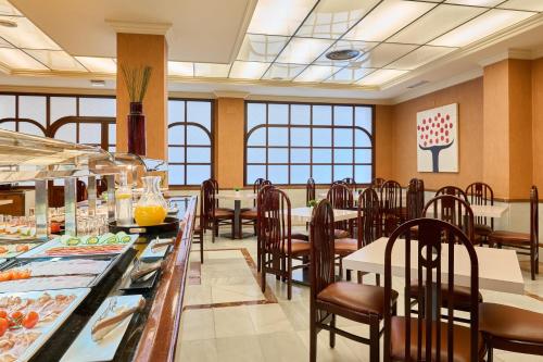 a restaurant with tables and chairs and a buffet at Hotel Macià Cóndor in Granada