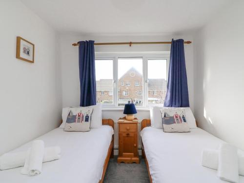 two twin beds in a room with a window at Home Waters in Weymouth
