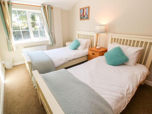 a bedroom with two beds and a window at Beach Way Cottage in Gorran Haven