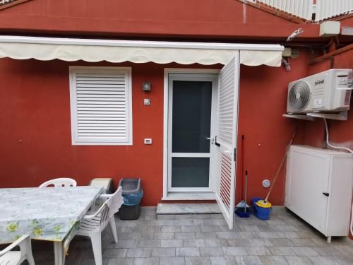 a red house with a table and a patio at Casina a Marina di Pisa in Marina di Pisa
