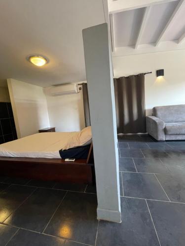 ein Schlafzimmer mit einem Bett und einem Sofa in einem Zimmer in der Unterkunft Appart Damazonie T1BIS calme idéalement situé in Montjoly