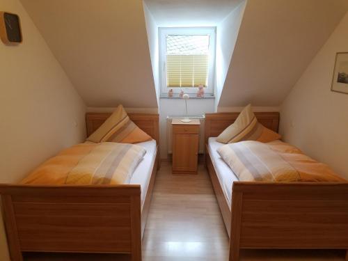 two beds in a small room with a window at Gästehaus Kloep GmbH in Hillesheim