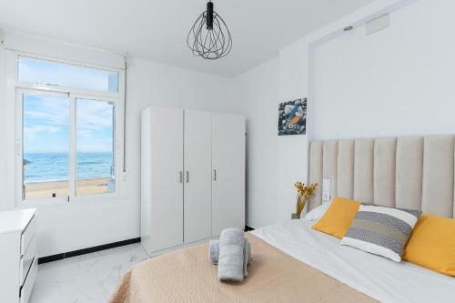 a white bedroom with a bed and a window at La Roca Chica in Torremolinos