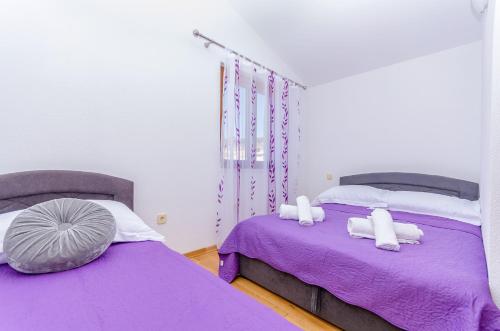 2 Betten in einem Zimmer mit lila Bettwäsche und Kissen in der Unterkunft Apartmani Selo Luka in Ražanj