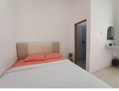 1 dormitorio con cama blanca y almohadas rosas en Brak Homestay, en Sukobumi