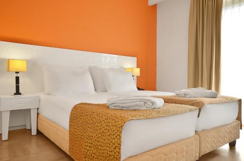two beds in a bedroom with an orange wall at Ruth Daniel Residence in Tel Aviv