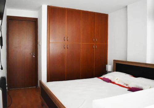 um quarto com uma cama e armários de madeira em Marina Apartment 4 em Lárnaca