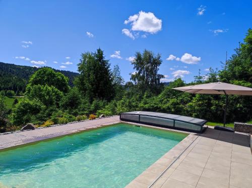 una piscina vacía con sombrilla y sombrilla en Le Cerf, chalet cocooning avec piscine et billard en Ban-sur-Meurthe-Clefcy