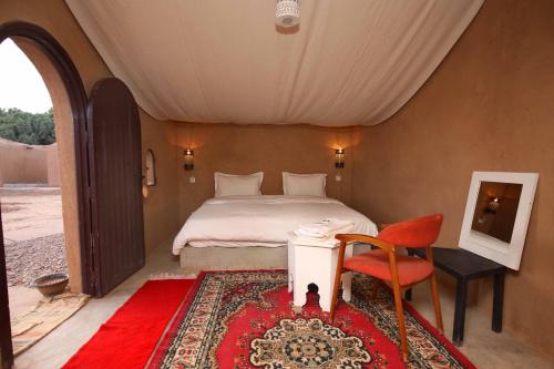 a bedroom with a bed and a table and a chair at HOTEL Bab Rimal in Foum Zguid