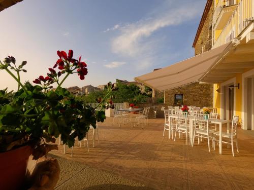 d'un patio avec des chaises blanches, des tables et des fleurs. dans l'établissement Palazzo Gargano, à Prignano Cilento