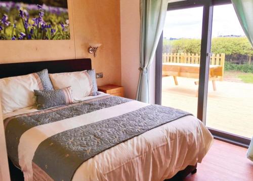 a bedroom with a bed with a view of a patio at Castle Pren Lodges in Llanddewi Ystradenny
