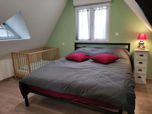 ein Bett mit zwei roten Kissen in einem Schlafzimmer in der Unterkunft Le grand gîte d'Angélique en Normandie - 4 personnes in Norville
