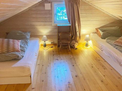 1 dormitorio en el ático con 2 camas y ventana en Holiday home FINNÅS II, 