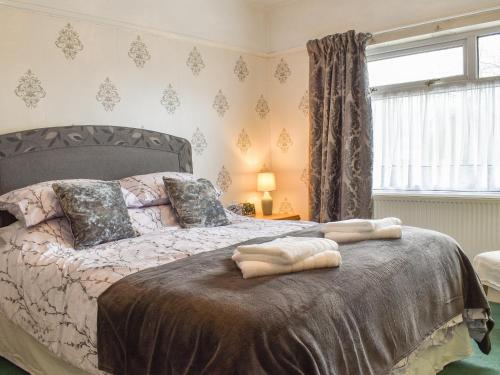 a bedroom with a bed with a blanket and a window at Maureg Formby in Formby