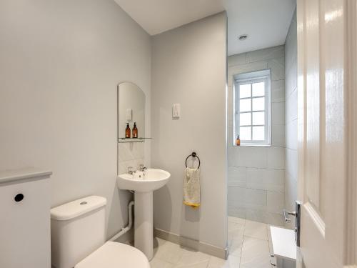 La salle de bains blanche est pourvue de toilettes et d'un lavabo. dans l'établissement Wisteria Cottage, à Horam
